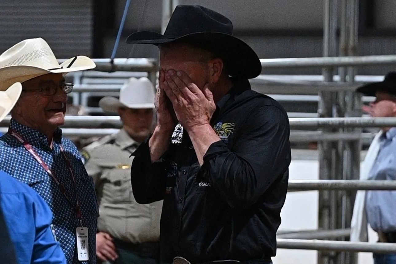 Cody Ohl, in a black hat and shirt, covers his face with both hands at the South Texas Showdown in Uvalde, Texas.